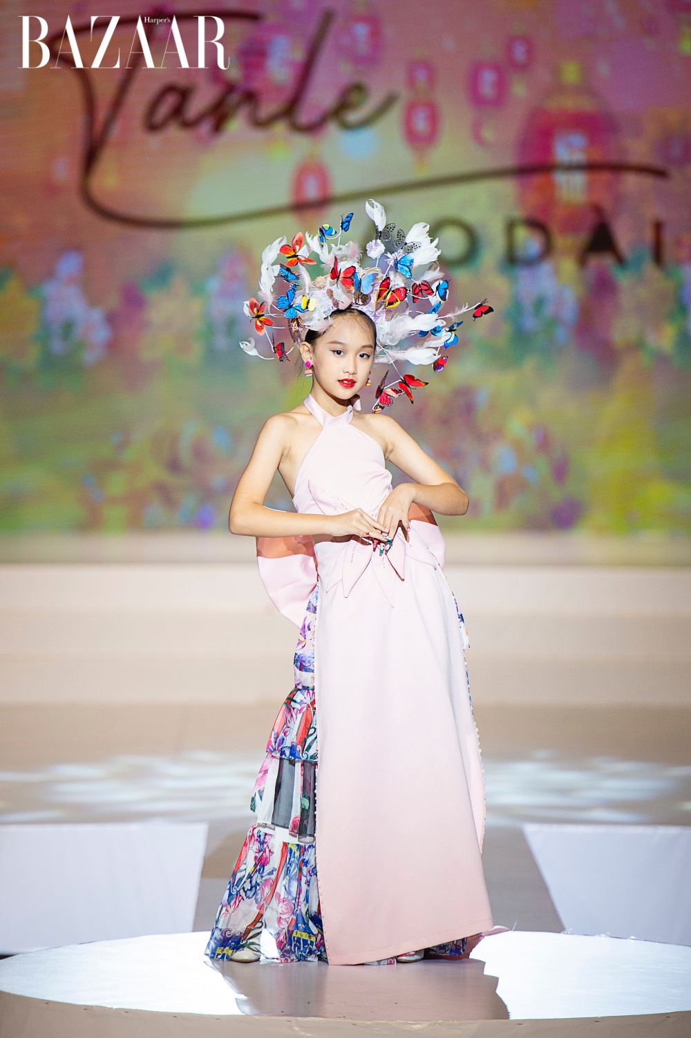 Mẫu nhí Nguyễn Đinh Ngọc Anh với chiếc áo dài hồng được thiết kết cầu kỳ ở phần thân áo cùng phụ kiện như một nàng tiên hoa toả sáng trên sàn diễn.