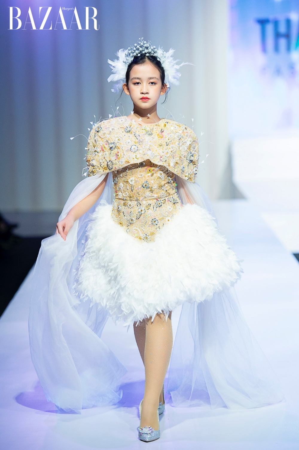 Là nàng thơ yêu thích của Thanh Hằng qua các bộ sưu tập, lần này cô bé Phạm Ngọc Khánh diện một thiết kế cầu kỳ với phần thân áo đính đá và chiếc váy trắng lông vũ.